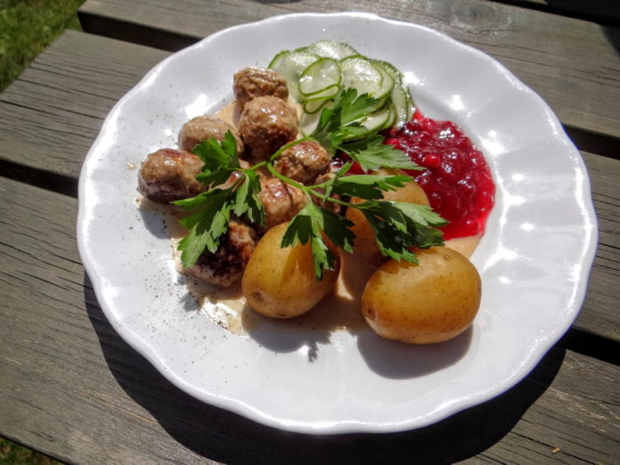 A plate of traditional Swedish meatballs (Köttbullar) with potatoes, gravy, and lingonberries